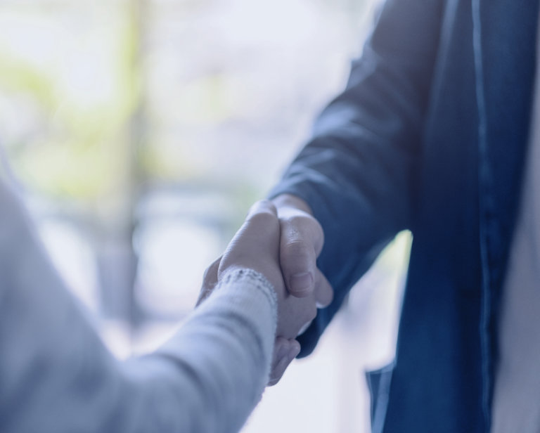 Two people in meeting shaking hands.