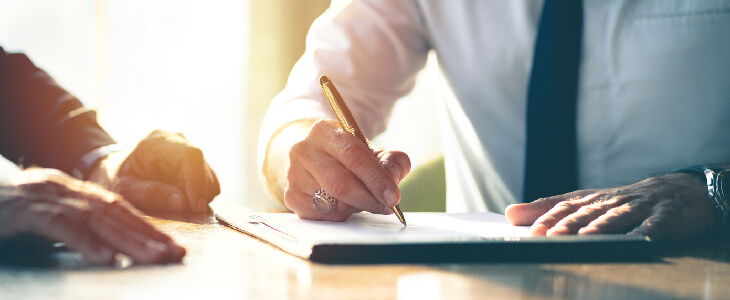 a professional writing on a pad on a desk with another person at the table employment law